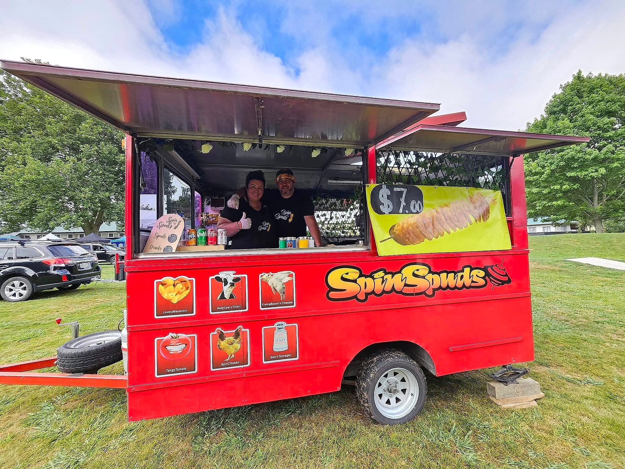 The SpinSpuds owners smiling at the serving window of their truck